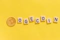 Cryptocurrency Dogecoin with letters on yellow background with hard shadows top view in close-up