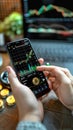 Cryptocurrency scene Hand holds Bitcoin, smartphone displays stock chart in cafe