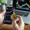 Cryptocurrency scene Hand holds Bitcoin, smartphone displays stock chart in cafe