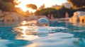 Crystal ball resting on rippling pool water, sunset reflection Royalty Free Stock Photo
