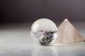 Crystal ball and rock crystal pyramid against a dark background