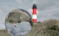 Crystal ball with an upside down lighthouse and the lighthouse next to it in the background