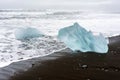 Crystal clear and blue ice chunks washes up on the black lava sand by the waves on diamond beach in Jokulsarlon glacier lagoon. Royalty Free Stock Photo