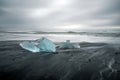 Crystal clear and blue ice chunks washes up on the black lava sand by the waves on diamond beach in Jokulsarlon glacier lagoon. Royalty Free Stock Photo