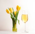 A crystal-clear flute glass of champagne or wine and a vase containing yellow tulips isolated on white background Royalty Free Stock Photo