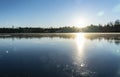 Crystal clear frozen lake in Northern Sweden - ice like big mirror. Low sun lights with warm light at very cold winter day