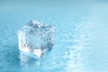 Crystal clear ice cube on light blue background, closeup. Space for text