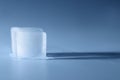 Crystal clear ice cube on light blue background, space for text Royalty Free Stock Photo