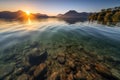 crystal clear lake, with view of mountain range and sunrise in the background Royalty Free Stock Photo