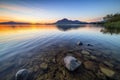 crystal clear lake, with view of mountain range and sunrise in the background Royalty Free Stock Photo