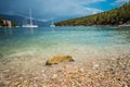 Crystal clear transparent blue turquoise teal mediterranean sea water of Foki Fiskardo Beach with some white yacht in Royalty Free Stock Photo