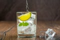 Crystal clear water pours into a glass with ice cubes, mint leaves and a slice of lime. Royalty Free Stock Photo