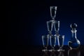 Crystal decanter or carafe of vodka and glasses pyramid tower on wooden table in restaurant, blue and black background with copy