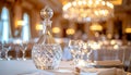 Crystal decanter with diamondcut pattern on formal dinner table with white linens and blurred chandelier background Royalty Free Stock Photo