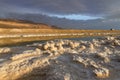 Crystal formations of mineral salts in the waters of the Dead Sea. Coastline with mountains on the horizon