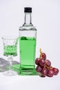 crystal glass and bottle of absinthe with branch of grapes