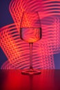 A crystal glass filled with pure water against a purple background and neon reddish streaks painted with light. Reflections, Royalty Free Stock Photo