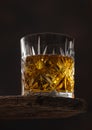 Crystal glass with ice cubes of scotch whiskey on top of wooden board and black Royalty Free Stock Photo