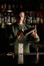 crystal glass with ice cubes stands on the bar counter and male bartender in background