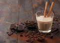 Crystal glass of Irish cream baileys liqueur with cinnamon, coffee beans and powder with dark chocolate on dark wood background Royalty Free Stock Photo