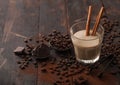 Crystal glass of Irish cream baileys liqueur with cinnamon, coffee beans and powder with dark chocolate on dark wood background Royalty Free Stock Photo