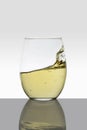 crystal glass with moving white wine making waves and white background Royalty Free Stock Photo