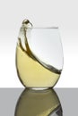 crystal glass with moving white wine making waves and white background Royalty Free Stock Photo