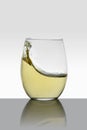 crystal glass with moving white wine making waves and white background Royalty Free Stock Photo