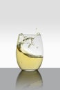 crystal glass with moving white wine making waves and white background Royalty Free Stock Photo