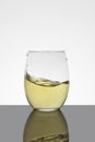 crystal glass with moving white wine making waves and white background Royalty Free Stock Photo