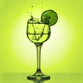 Crystal glass with a piece of lime and a splash on a bright green background Royalty Free Stock Photo