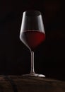 Crystal glass of red wine on top of wooden barrel on black