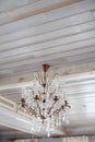 Crystal glass vintage chandelier hanging on wooden light ceiling Royalty Free Stock Photo