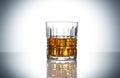 Crystal glass of whiskey with ice cubes on grey gradient background Royalty Free Stock Photo