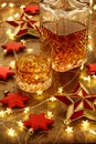 Crystal glass of whisky and a whisky decanter with christmas lights, baubles and red stars decorations Royalty Free Stock Photo