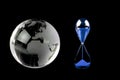 Crystal globe and blue hourglass on black background Royalty Free Stock Photo