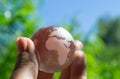 Crystal globe in the hand of a man against a background of blue sky and green foliage. Earth protection concept. Royalty Free Stock Photo