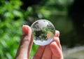 Crystal globe in the hand of a man against a background of green foliage. Earth protection concept. Earth Day Royalty Free Stock Photo