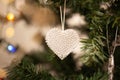 Crystal heart Christmas tree ornament on green branch with string lights and copy space. Winter love card