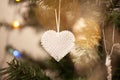 Crystal heart Christmas tree ornament on green branch with string lights and copy space. Winter love card