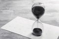 Crystal hourglass with black sand and calendar on grey table