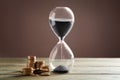 Crystal hourglass with black sand and coins on color wooden table. Time is money