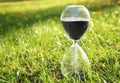 Crystal hourglass with black sand on green grass outdoors