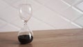 Crystal hourglass with black sand on wooden table