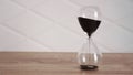 Crystal hourglass with black sand on wooden table