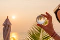 Lens ball in hand with reflection of sea and sunset on the beach Royalty Free Stock Photo