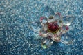 Crystal lotus on blue shiny sequins table. Vishuddha chakra symbol. Reiki meditation