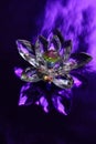 Crystal lotus on shiny dark purple table. Stone flower with light reflect. Sahasrara chakra symbol