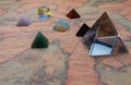 Crystal pyramide and small pyramids of natural gemstones with light cube on an ancient world map