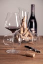 Crystal red wine glass, bottle, corkscrew, opener, sommelier knife, transparent decanter, corks on wooden table. Closeup Royalty Free Stock Photo